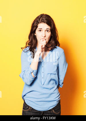 Portrait of young woman biting nails nerveux contre fond jaune Banque D'Images