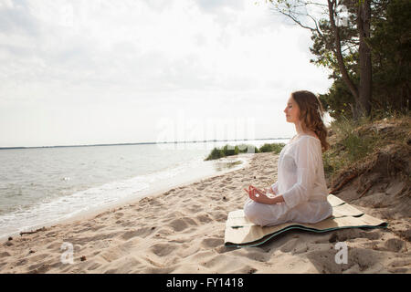 Woman meditating on sea shore à la sky Banque D'Images