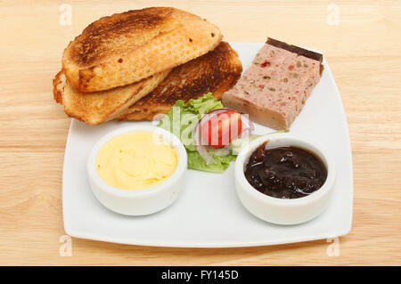 Pate ferme et de pain grillé sur une plaque sur une table en bois Banque D'Images