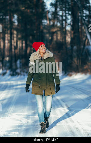 Longueur totale de happy woman walking on snow covered field Banque D'Images