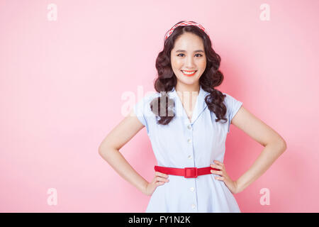 Portrait of young smiling woman style rétro en plaçant ses mains sur ses reins fixant à l'avant Banque D'Images