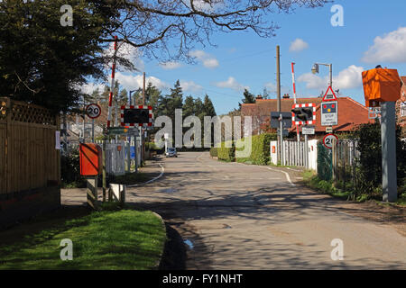 Une barrière de passage à niveau automatique de la moitié en zone rurale avec beaucoup de signalisation et antérieus de chaque côté de l'appareil photo. Banque D'Images