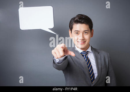 Portrait of young smiling businessman with une bulle pointant vers l'avant à l'avant Banque D'Images