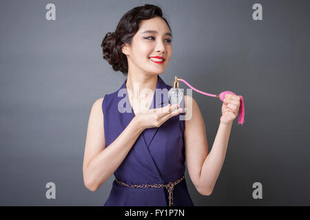 Portrait of young smiling woman in retro style spraying perfume Banque D'Images