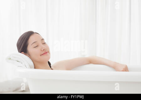 Side view of young woman relaxing fermer les yeux dans la baignoire rideau contre Banque D'Images