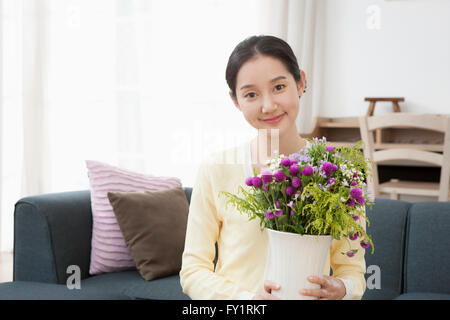 Portrait of young smiling woman holding fleurs dans un vase Banque D'Images