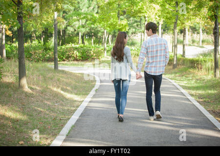 Dos de jeune couple marche main dans la main au parc Banque D'Images