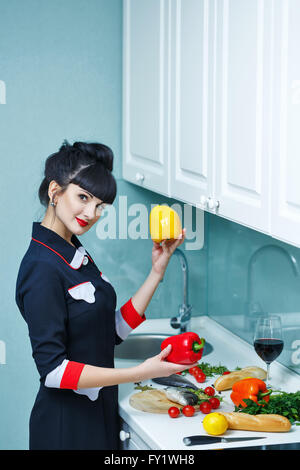 Jeune fille mince dans la cuisine. Girl choisit des légumes pour le dîner. Les tâches ménagères. Banque D'Images