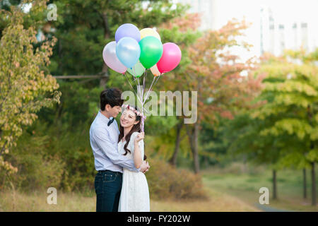 Bride and Groom standing at the park with balloons Banque D'Images