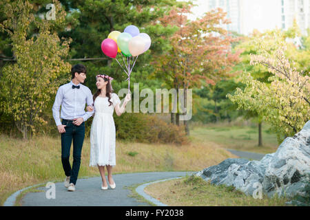 Bride and Groom standing at park with balloons Banque D'Images