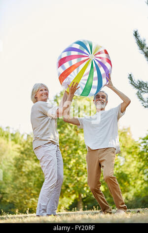 Happy senior couple jetant une grosse boule sur leur maison de vacances Banque D'Images