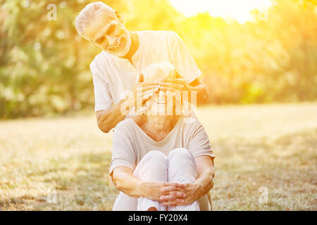 Vieil homme couvre smiling woman's eyes en été dans le jardin Banque D'Images