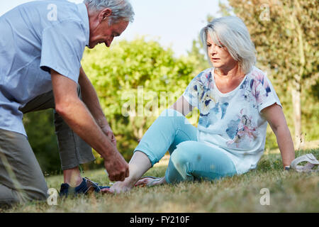 Vieil homme femme aide avec l'entorse de la cheville dans la nature Banque D'Images