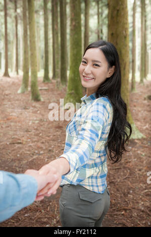 Femme tirant sur la main de l'homme dans les bois Banque D'Images