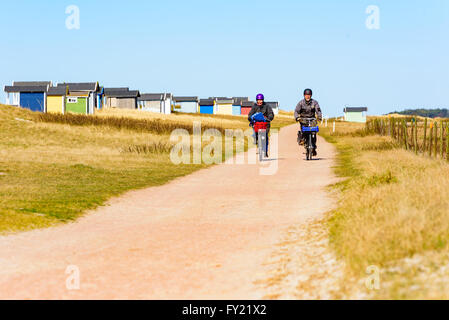 Skanor, Suède - 11 Avril 2016 : un couple de personnes âgées n'est pas faire du vélo sur la route à la plage le long des cabines de bain. Les deux nous Banque D'Images