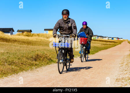 Skanor, Suède - 11 Avril 2016 : un couple de personnes âgées n'est pas faire du vélo sur la route à la plage le long des cabines de bain. Les deux nous Banque D'Images