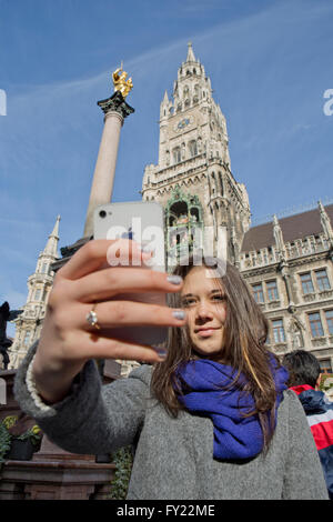 Fille, 14 ans, de prendre un en selfies avant de la colonne mariale à la place Marienplatz, nouvel hôtel de ville, Munich, Haute-Bavière Banque D'Images