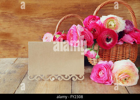 Fleurs roses dans le panier à côté de carte vide, sur la table en bois. copier l'espace. Banque D'Images