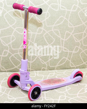 Les petits enfants à trois roues scooter rose sur la table Banque D'Images
