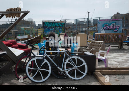 Deux jeunes hommes travaillant sur ordinateur portable dans la communauté nomade Gardens à Tower Hamlets, un vélo Banque D'Images