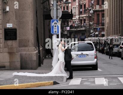 Mariée et le marié s'embrasser dans les rues de Shanghai. Groom holding le bouquet. Banque D'Images