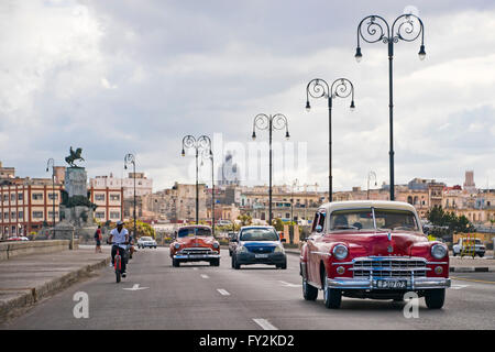 Vue horizontale de voitures américaines classiques roulant sur le Malecon à La Havane, Cuba. Banque D'Images