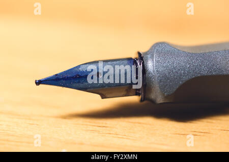 Fermer l'accent sur l'encre bleue humide nib de stylo sur la table en bois floue Banque D'Images