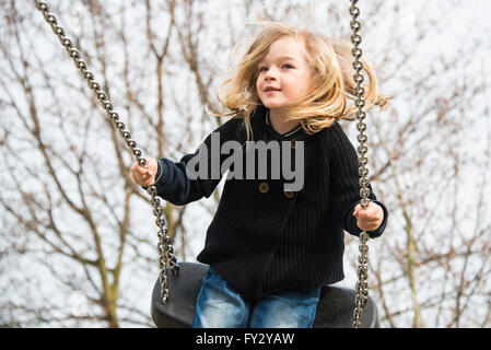 Petit enfant fille blonde s'amusant sur une balançoire à l'extérieur. Jeux d'été. Haut fille se balançant Banque D'Images