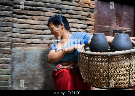 Femme locale transports pots pour sécher au soleil, Place Pottery, Bhaktapur, Népal Banque D'Images