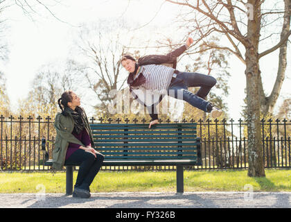 Jeune homme essayant d'impressionner indifférent girl en sautant par dessus un banc de parc, Suède