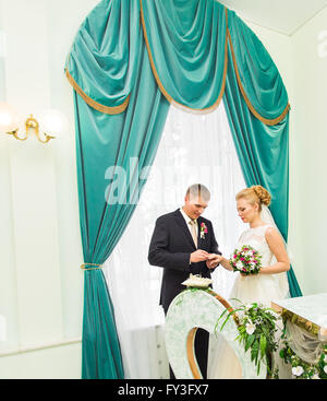 Le marié de glisser sur le doigt de l'anneau de mariage à la mariée Banque D'Images