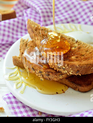 Verser le miel sur toast - petit déjeuner Banque D'Images