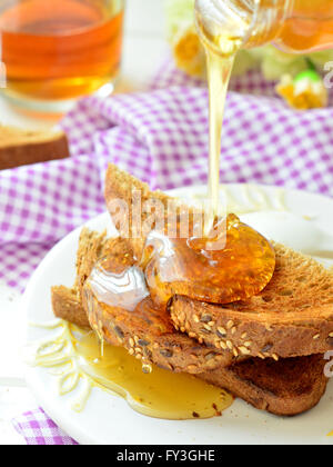 Verser le miel sur toast - petit déjeuner Banque D'Images