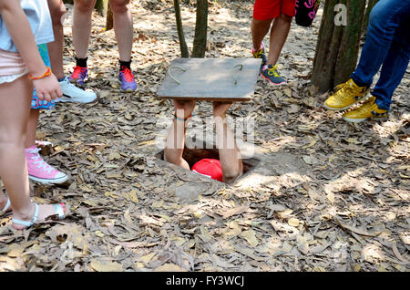 Les gens voyagent et essayer de jouer la saisie au tunnel Tunnels de Cu Chi à Ho Chi Minh, Vietnam Banque D'Images