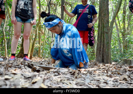 Les gens voyagent et essayer de jouer la saisie au tunnel Tunnels de Cu Chi à Ho Chi Minh, Vietnam Banque D'Images