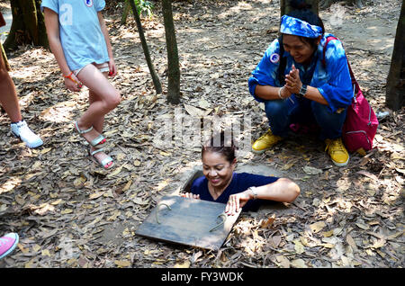 Les gens voyagent et essayer de jouer la saisie au tunnel Tunnels de Cu Chi à Ho Chi Minh, Vietnam Banque D'Images