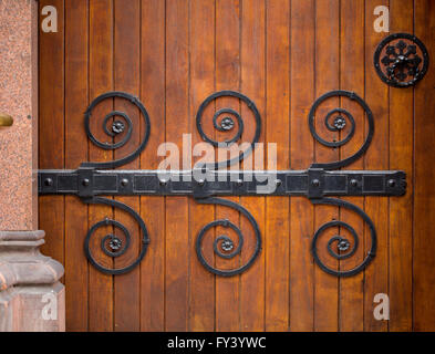 Porte ouvragée. Une belle vieille énorme porte en bois ornée de motifs en métal a elle qui sont utilisés pour maintenir la porte ensemble. Banque D'Images