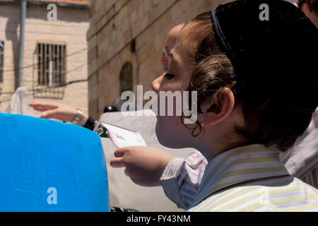 Jérusalem, Israël. 21 avril, 2016. Un garçon ultra-orthodoxe juif haredi montres comme hommes plats dip et les ustensiles dans l'eau bouillante pour la purification avant la Pâque. Un rituel important est l'élimination de hametz, tout produit alimentaire qui contient du levain Blé, avoine, orge, seigle, épeautre ou produits. La loi est symbolique de l'exode biblique des anciens Hébreux de l'esclavage en Egypte à la liberté, à qui n'ayant pas eu le temps d'attendre pour pâte d'augmenter avant de quitter l'Egypte, ils partirent dans le désert avec des pains sans levain. Credit : Alon Nir/Alamy Live News Banque D'Images