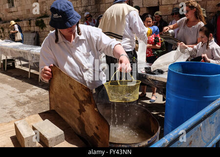 Jérusalem, Israël. 21 avril, 2016. Les hommes juifs tremper la vaisselle et les ustensiles dans l'eau bouillante pour la purification avant la Pâque. Un rituel important est l'élimination de hametz, tout produit alimentaire qui contient du levain Blé, avoine, orge, seigle, épeautre ou produits. La loi est symbolique de l'exode biblique des anciens Hébreux de l'esclavage en Egypte à la liberté, à qui n'ayant pas eu le temps d'attendre pour pâte d'augmenter avant de quitter l'Egypte, ils partirent dans le désert avec des pains sans levain. Credit : Alon Nir/Alamy Live News Banque D'Images