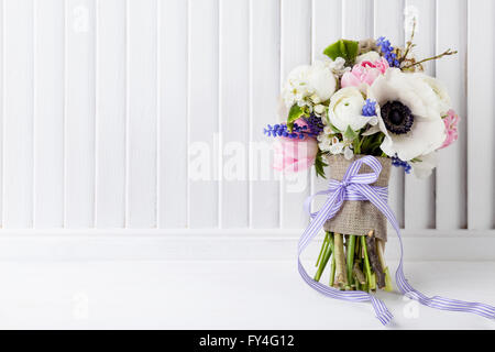 Bouquet de tulipes roses, violettes, muscaris anémones blanc, violet et blanc veronica buttercup avec ruban violet sur whit Banque D'Images