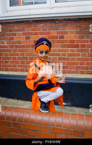 Un petit garçon mange de la barbe à papa dans son costume de parade en attendant le début de la célébrations du Vaisakhi à Southampton (UK) Banque D'Images