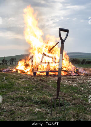 Une fourche à bêcher creusé dans le sol en face d'un feu allumé phare pour le 90e anniversaire de la reine, en Whitwell, île de Wight, Royaume-Uni Banque D'Images