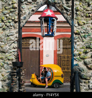 Vue sur place grâce à l'arcade à Hamel's Alley d'un cocotaxi à La Havane, Cuba. Banque D'Images