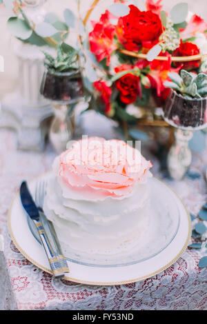 Morceau de gâteau de mariage en rose sur la table avec des fleurs de près. Jour de mariage Banque D'Images