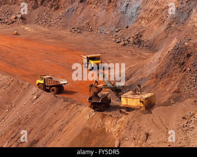 La charge de la pelle de la carrière du minerai de fer à big dump truck dans la mine à ciel ouvert avec un autre deux camions en attente dans la file d'attente Banque D'Images