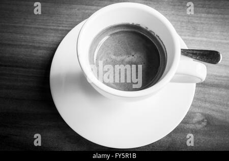 White tasse de café expresso fraîchement préparé sur une soucoupe avec une cuillère. Photo en noir et blanc avec selective focus Banque D'Images