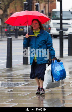 Londres, Royaume-Uni. 22 avril 2016. Une femme marche avec un parapluie dans le centre de Londres sous la pluie et le temps humide de cet après-midi. Credit : Londres pix/Alamy Live News Banque D'Images