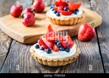 Dessert de fruits tartes à la crème, fraises, bleuets et sur table en bois Banque D'Images
