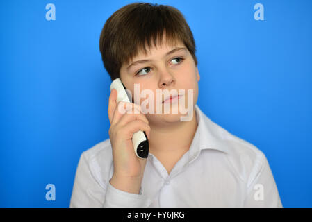 Teen boy talking en radiotéléphonie sur fond bleu Banque D'Images