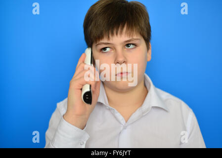 Teen boy talking en radiotéléphonie sur fond bleu Banque D'Images